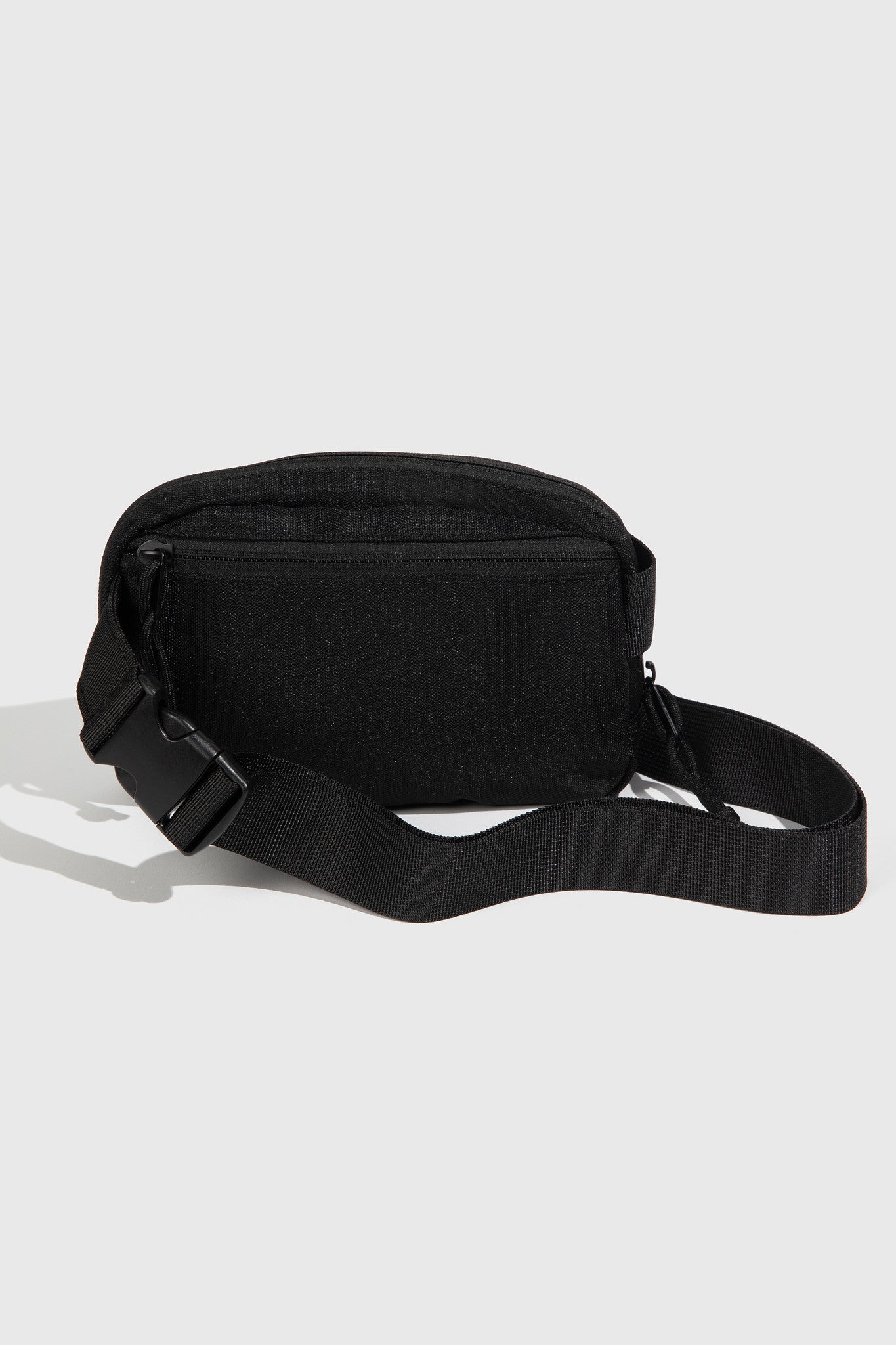 Black (Re)volution™ 1L Go-Anywhere Bag (Angle): Black canvas fanny pack showing back zipper pocket and adjustable buckle strap