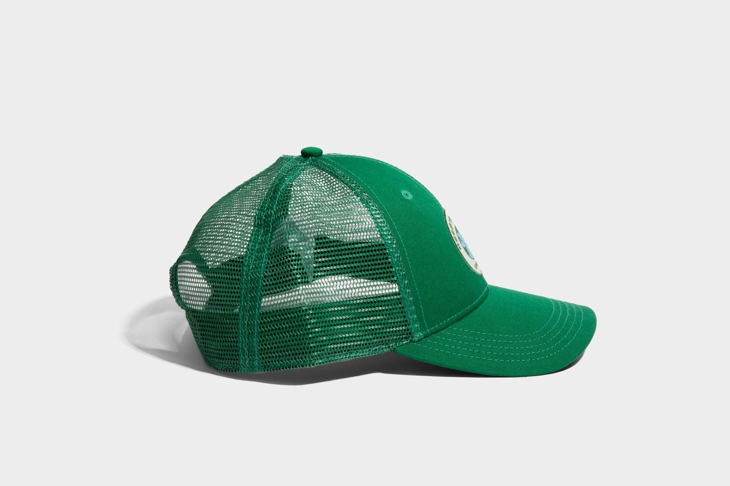 PINE ORGANIC TRUCKER HAT (Angle): Green trucker cap with mesh back panels and embroidered front patch