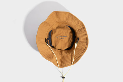 HONEY UTILITY BUCKET HAT (Detail): Interior view of amber bucket hat showing label, chin cord, and clips