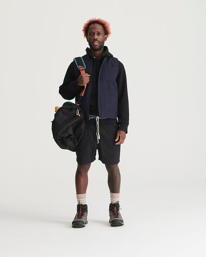 Black Recycled Sport Short (In-use): Man wearing black drawstring shorts with hiking boots and navy vest