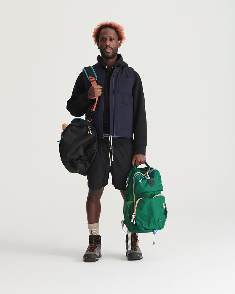 Black Recycled Sport Short (In-use): Man wearing black shorts with drawstring waist, holding multiple bags