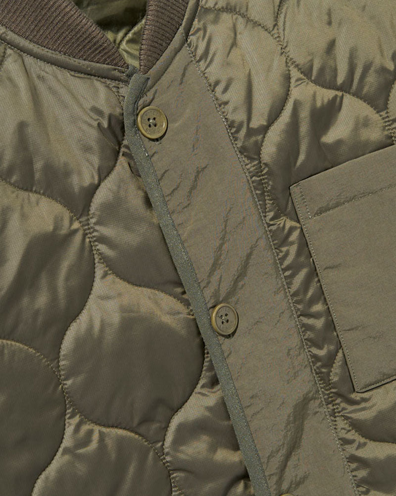 Forest Floor Bison Ultralight Liner Jacket (Detail): Olive quilted fabric with two brass buttons and a chest pocket visible