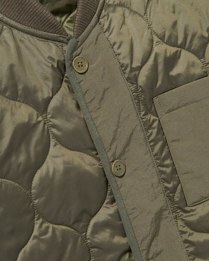 Forest Floor Bison Ultralight Liner Jacket (Detail): Olive quilted fabric with two brass buttons and a chest pocket visible