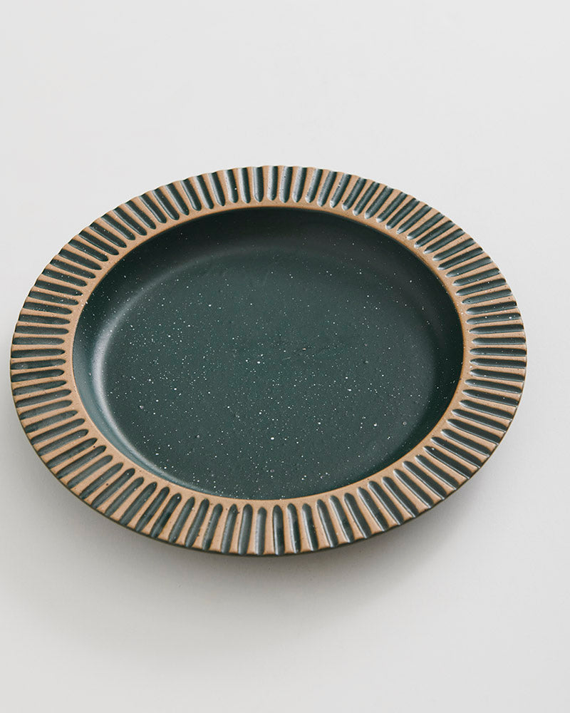 Pine Stoneware Stackable Plate (Angle): Round ceramic plate with ribbed tan rim and speckled dark green center