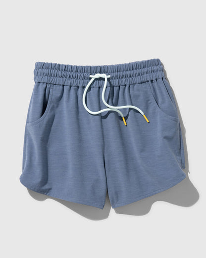 Stone Blue The Responsible Swim Short (Flat-lay): Slate blue drawstring shorts with white cord, yellow tips, side pockets