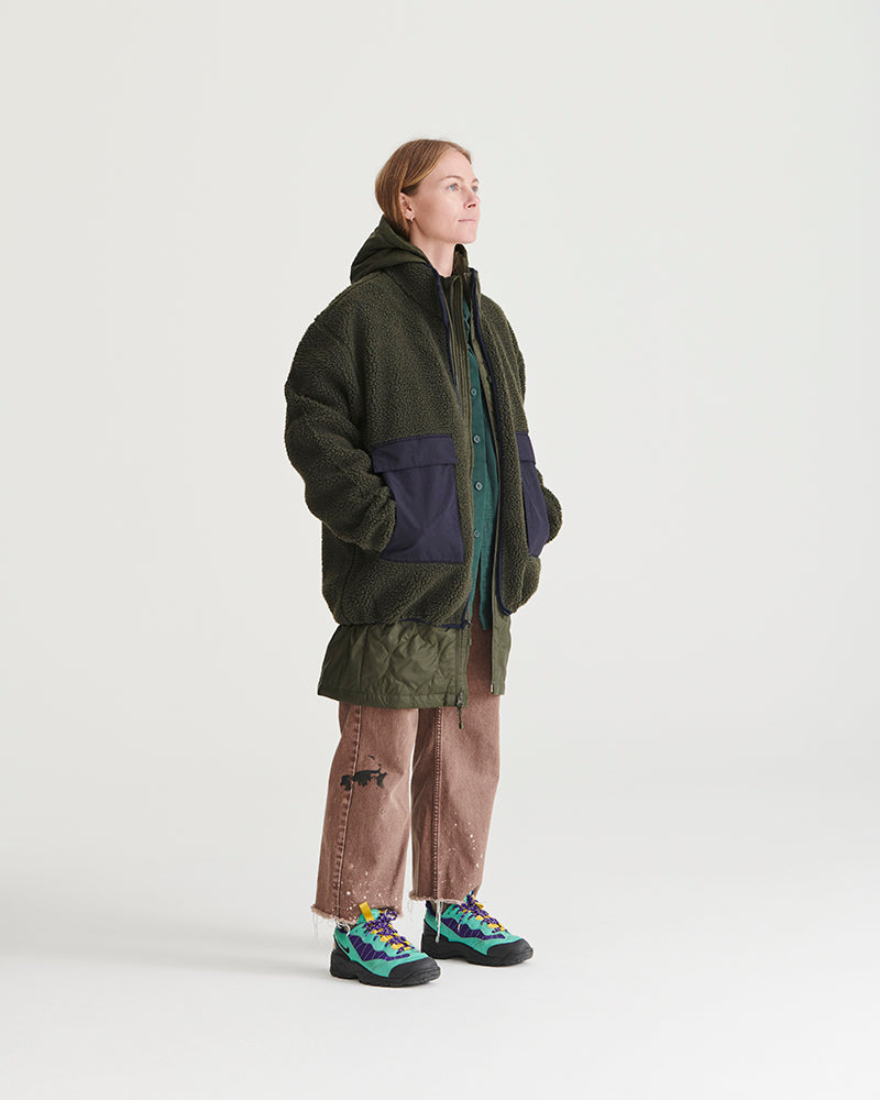 Forest Floor Bison Ultralight Long Liner Jacket (In-use): Woman wearing dark olive sherpa jacket with navy nylon pocket panels layered over hoodie