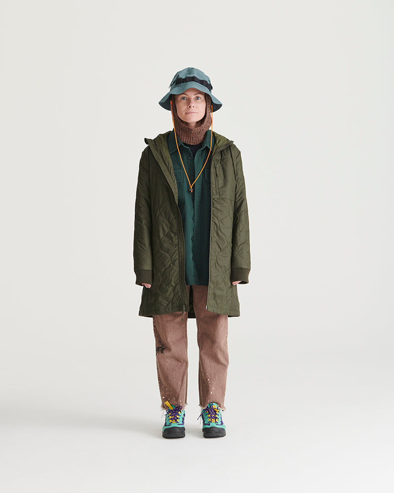 Forest Floor Bison Ultralight Long Liner Jacket (In-use): Person wearing open olive quilted long coat, brown pants, colorful boots