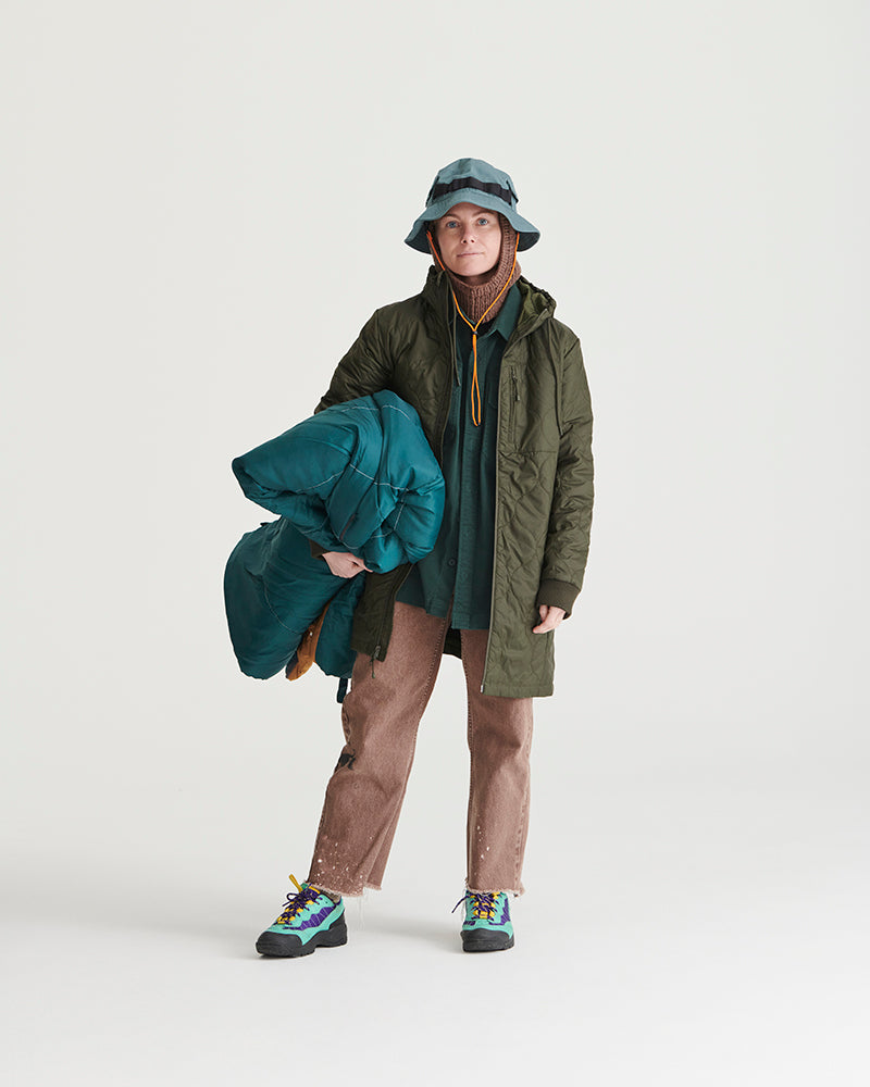 Forest Floor Bison Ultralight Long Liner Jacket (In-use): Person wearing forest green quilted long liner jacket, carrying teal blanket