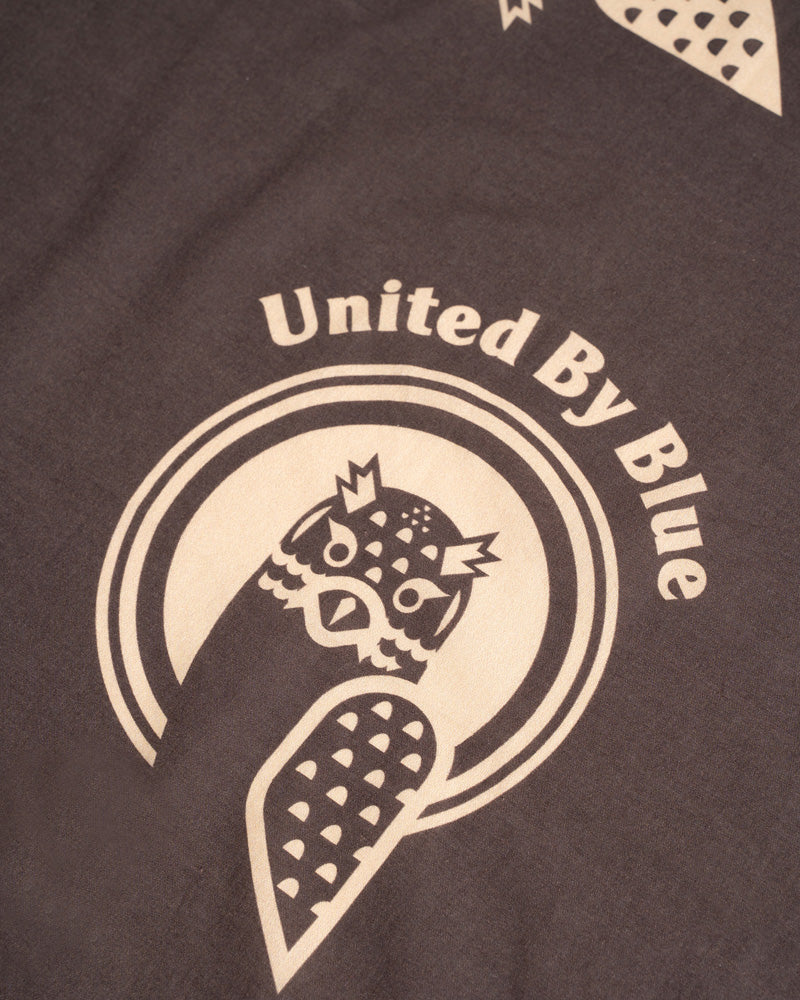 Dark Brown Organic Hoot Bandana (Detail): Dark brown bandana with cream owl logo and United By Blue text
