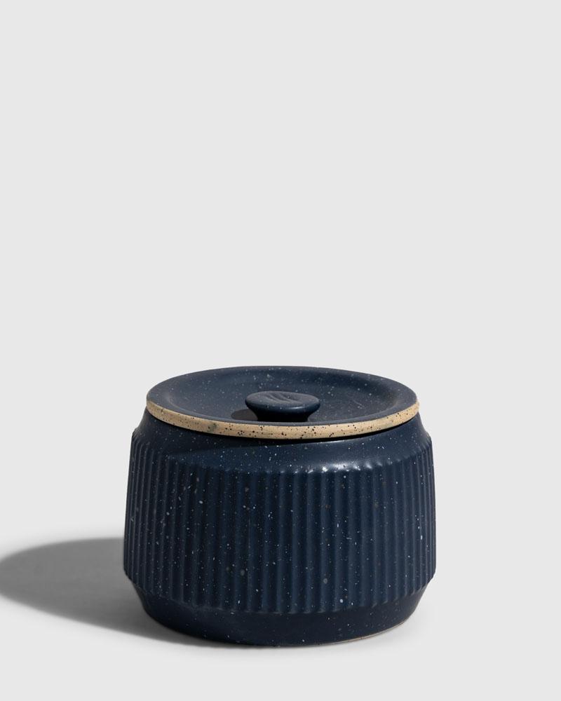 INDIGO 14 oz. Ceramic Keepsake Candle - Surf (Front): Dark navy speckled ceramic jar with ribbed sides and fitted lid
