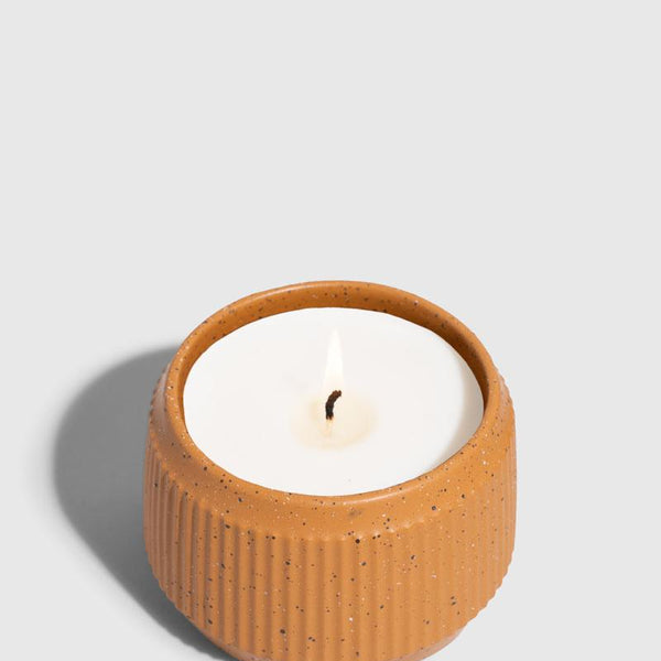 CARAMEL 14 oz. Ceramic Keepsake Candle - Mountain Peak (Angle): Round ribbed speckled terracotta ceramic vessel holds white wax with lit wick