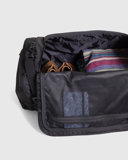 Black (R)evolution™ 55L Carry-On Duffle (Detail): Open black duffle interior showing mesh divider, sandals, striped blanket, bottle