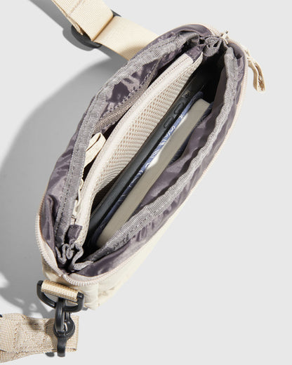 Sand (Re)active™ 2L Convertible Crossbody (Detail): Open cream crossbody bag interior showing phone, card, and mesh pocket