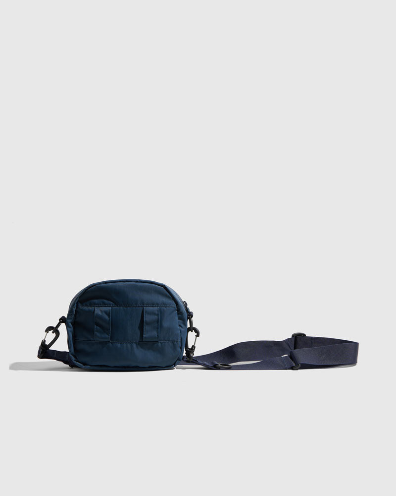 Deep Sea (Re)active™ 2L Convertible Crossbody (Angle): Navy blue small crossbody bag with front pocket and adjustable strap