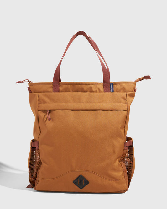 Camel (R)evolution™ 25L Convertible Carryall (Front): Tan tote bag with rust straps, front zip pocket, mesh side pockets