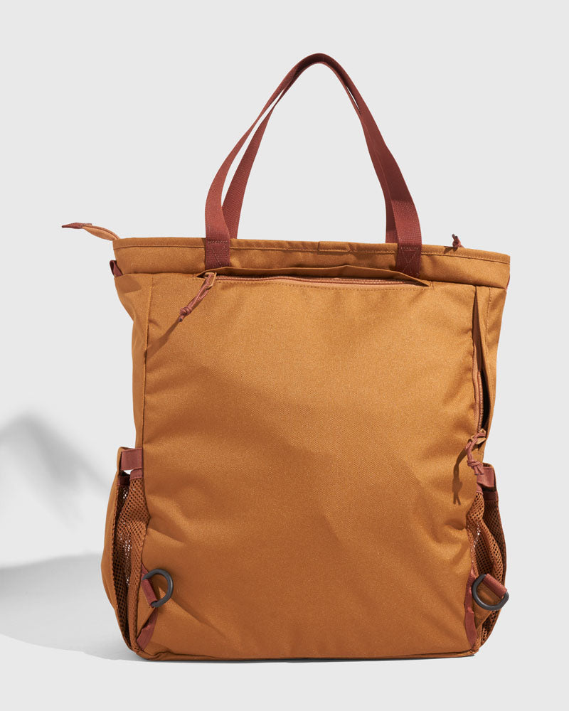 Camel (R)evolution™ 25L Convertible Carryall (Back): Tan tote with dark red handles, side mesh pockets, and D-rings