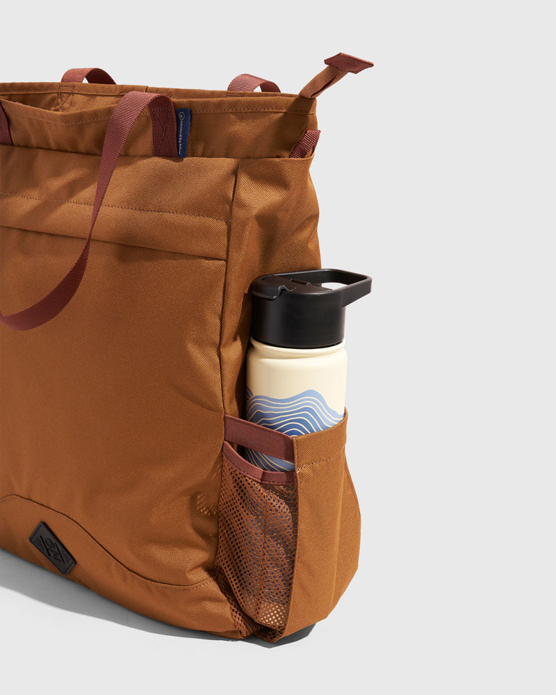 Camel (R)evolution™ 25L Convertible Carryall (Detail): Close-up of tan bag's mesh side pocket holding a water bottle