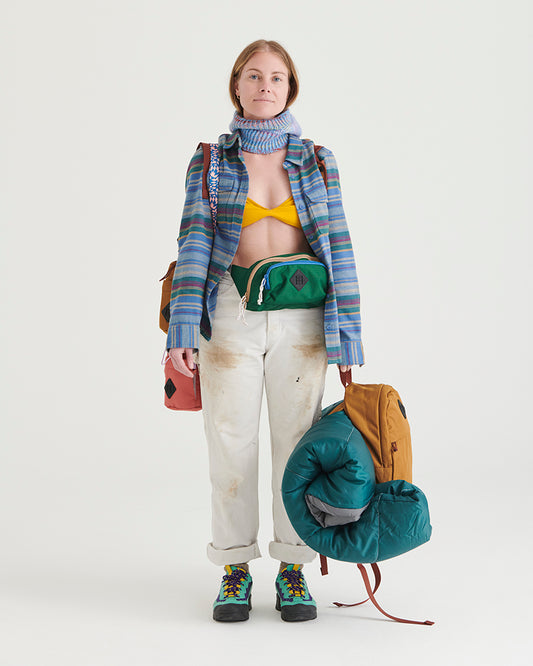 Pine (R)evolution™ 3L Utility Fanny Pack (In-use): Woman wearing green fanny pack around waist, open striped shirt, white pants