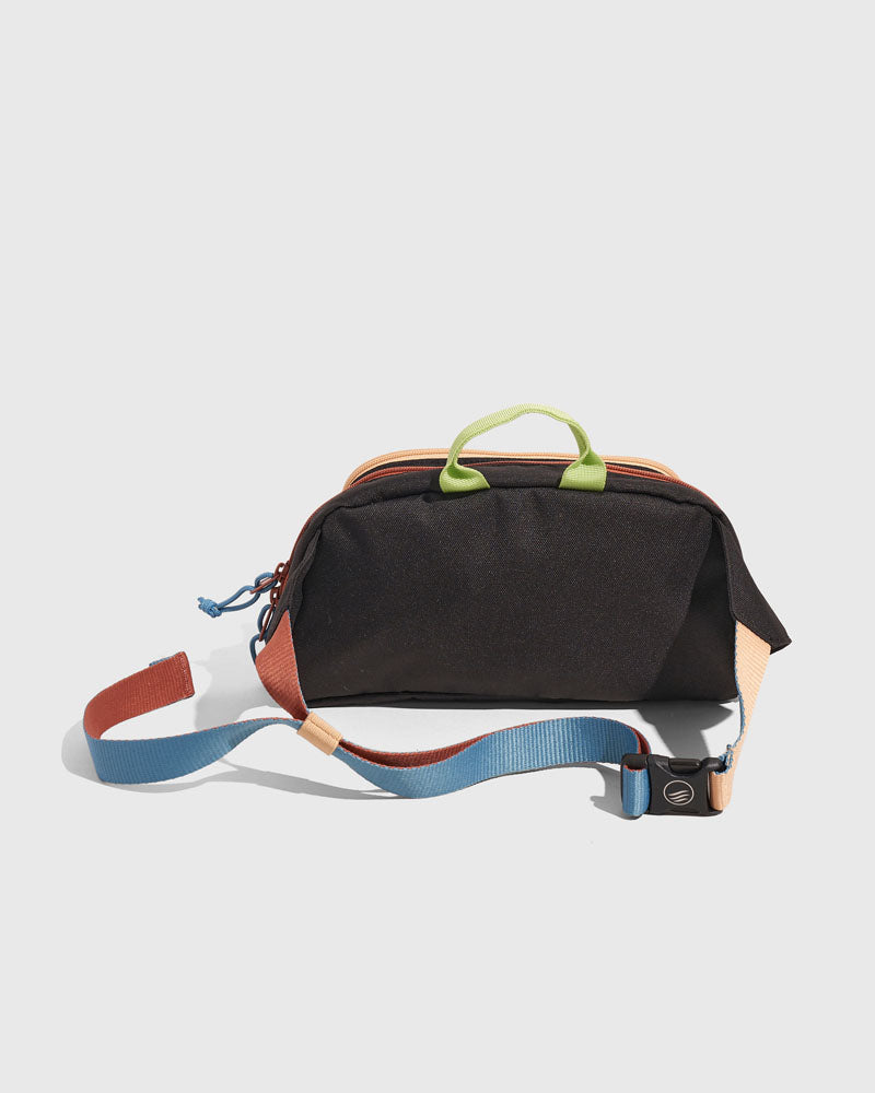 Black Multi (R)evolution™ 3L Utility Fanny Pack (Angle): Black fanny pack with peach trim, green handle, multicolor buckle strap