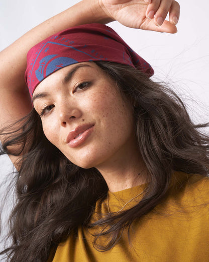 Beet Organic Bandana (In-use): Woman wearing dark red bandana as headband, blue mountain print