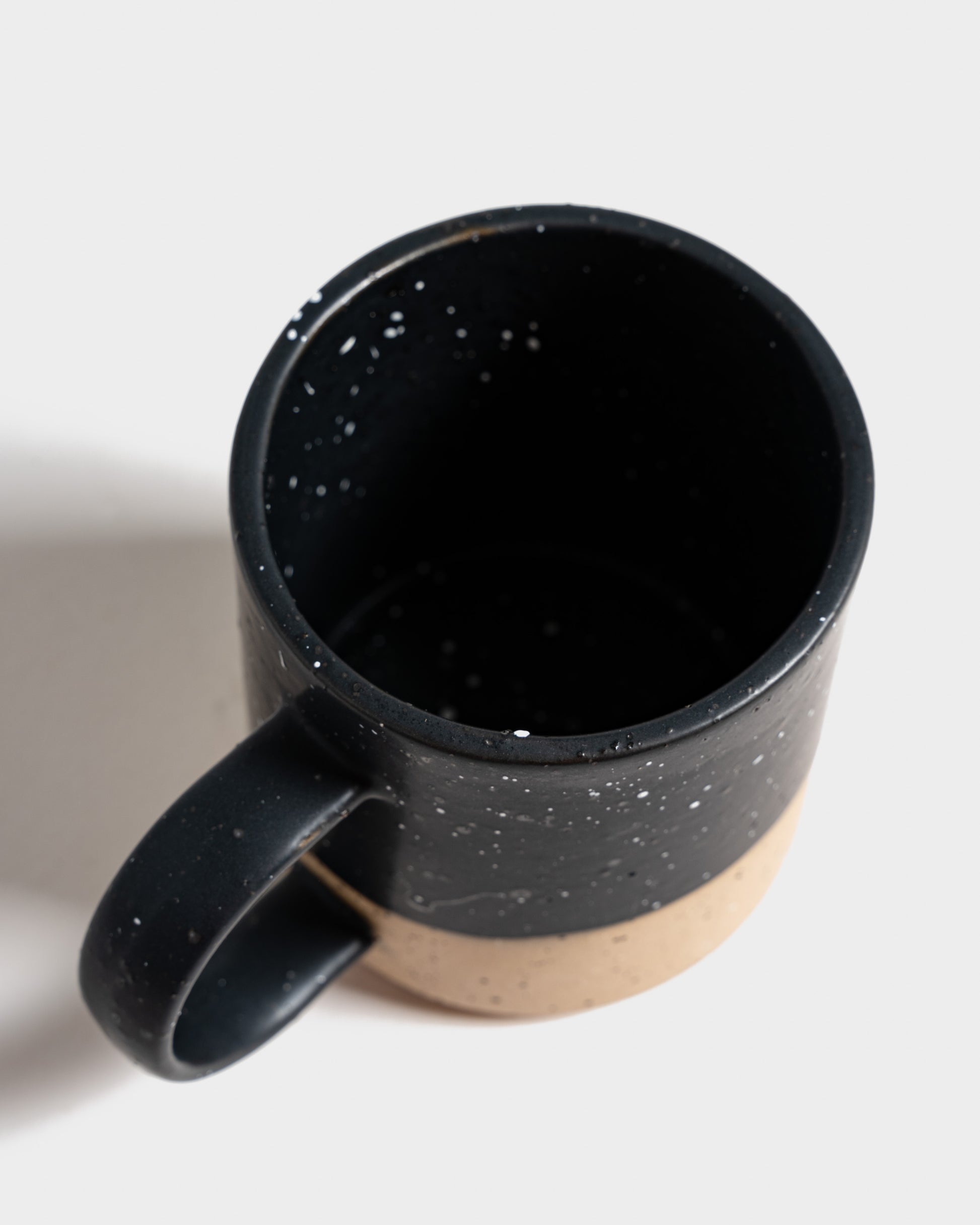 Black 8 oz. Stoneware Mug (Detail): Overhead view into matte black speckled interior; unglazed tan lower half visible