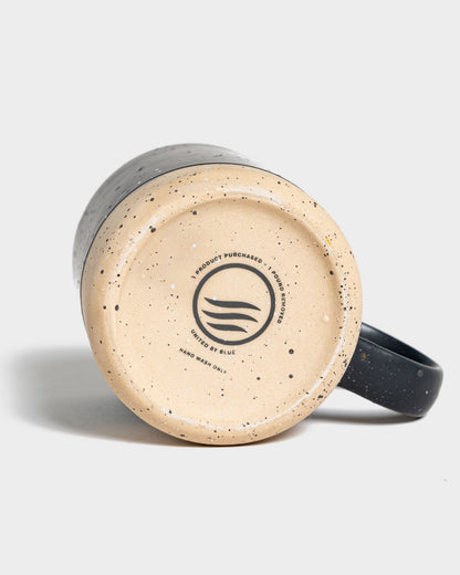 Black 8 oz. Stoneware Mug (Detail): Bottom of dark speckled stoneware mug showing brand logo and care text