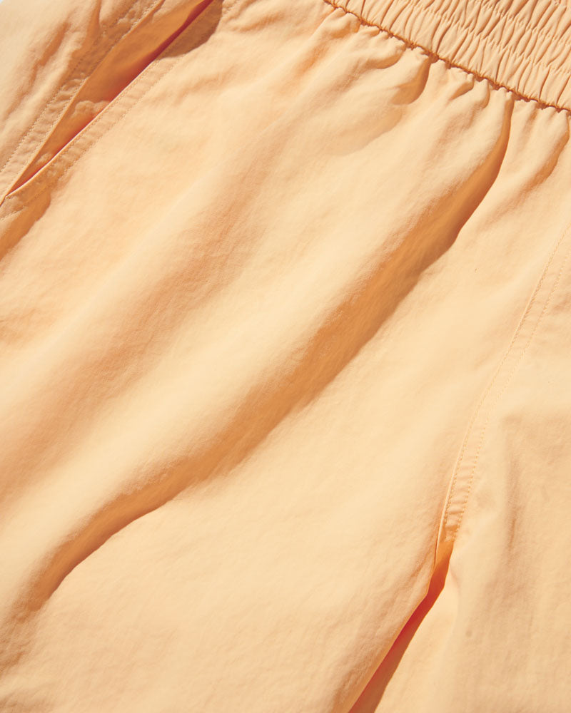 Buff Orange Recycled Sport Short (Detail): Close-up of smocked elastic waistband and lightweight peach-toned fabric