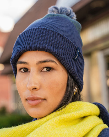NAVY Recycled Chevron Pom Beanie (In-use): Woman wearing navy ribbed pom beanie with yellow scarf outdoors