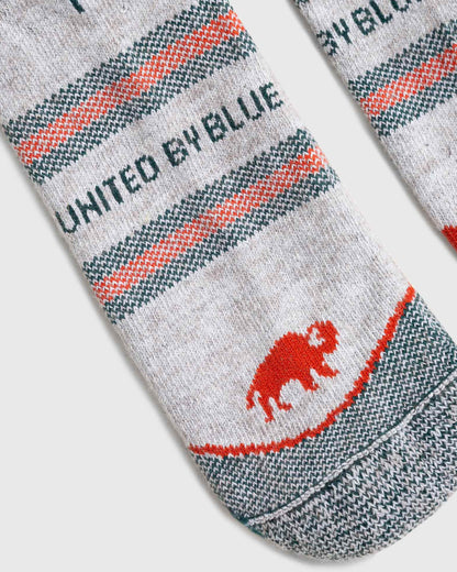 Green Bison Wool Trail Sock (Detail): Close-up of heather grey sock with red and teal stripes and bison logo