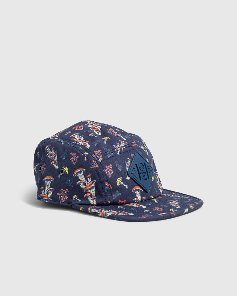 Navy Mushrooms Organic 5-Panel Hat (Angle): Navy five-panel cap with mushroom print and diamond-shaped logo patch