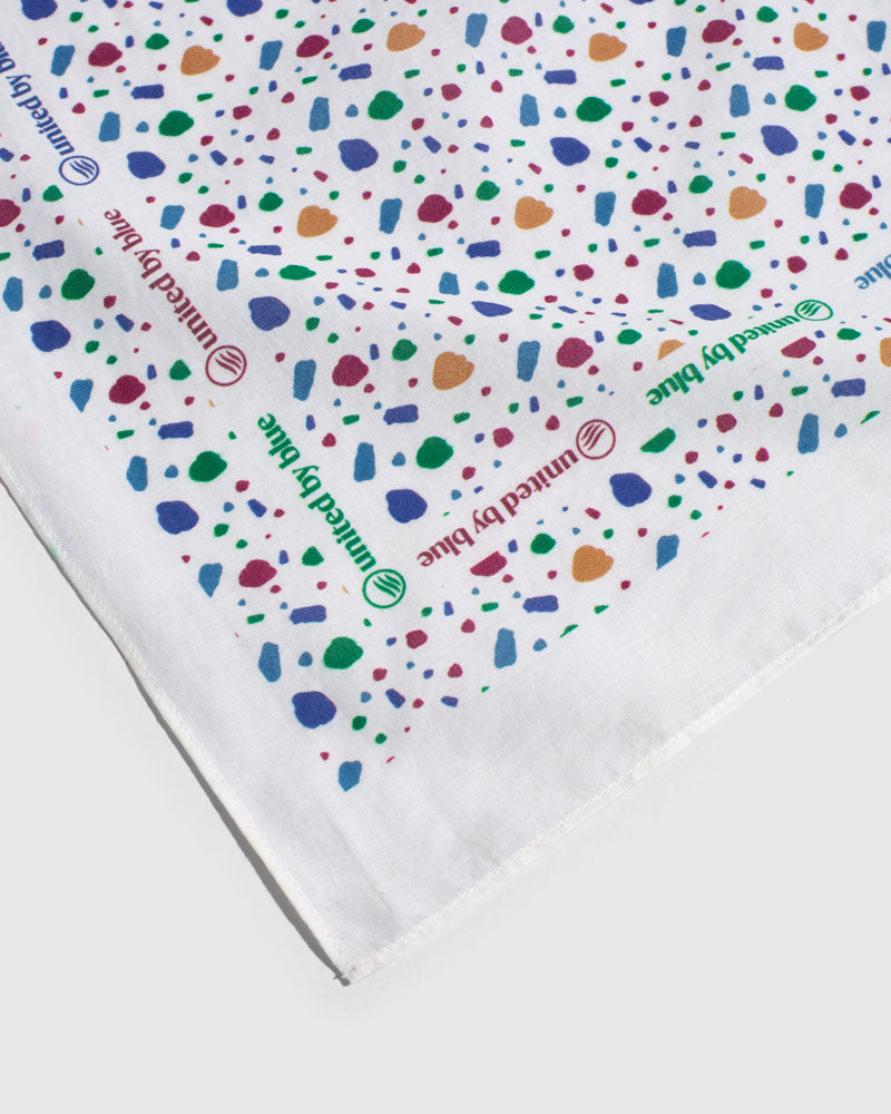 Egret Organic Bandana (Detail): White bandana with colorful terrazzo shapes and repeated brand logo text