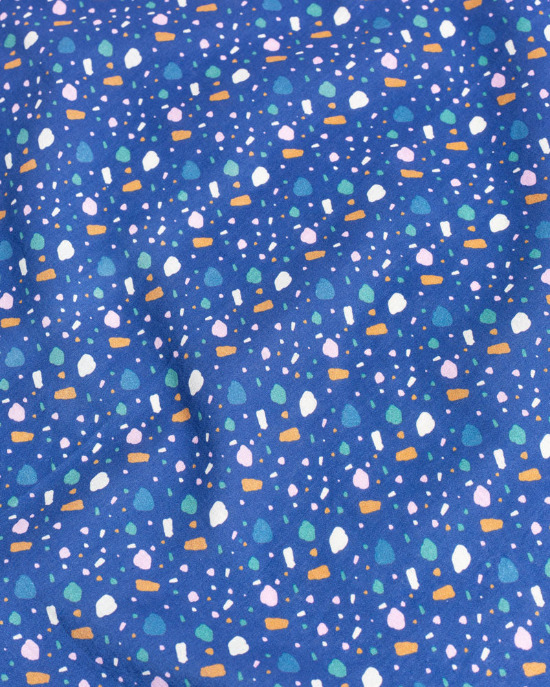 Lagoon Organic Bandana (Detail): Blue fabric with scattered multicolor confetti shapes in white, pink, green, and orange