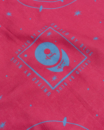 Beet Organic Bandana (Detail): Close-up of blue diamond logo and star pattern on pink fabric