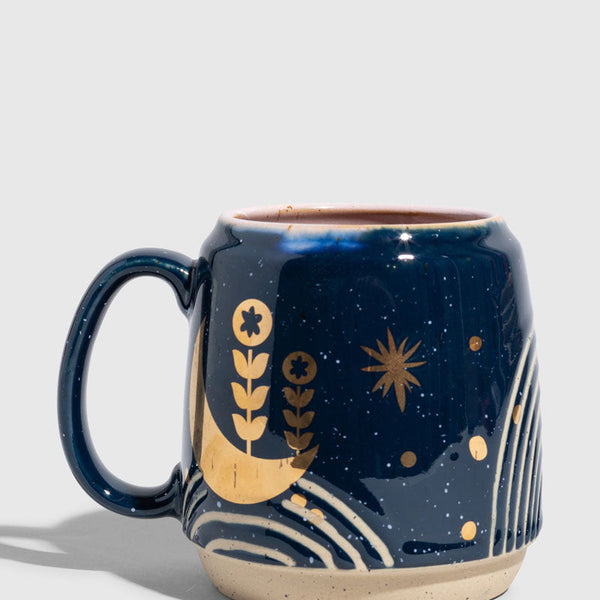 Nightfall Blue 16 oz. Stoneware Mug (Angle): Dark blue stoneware mug with gold moon, botanicals, and star motifs