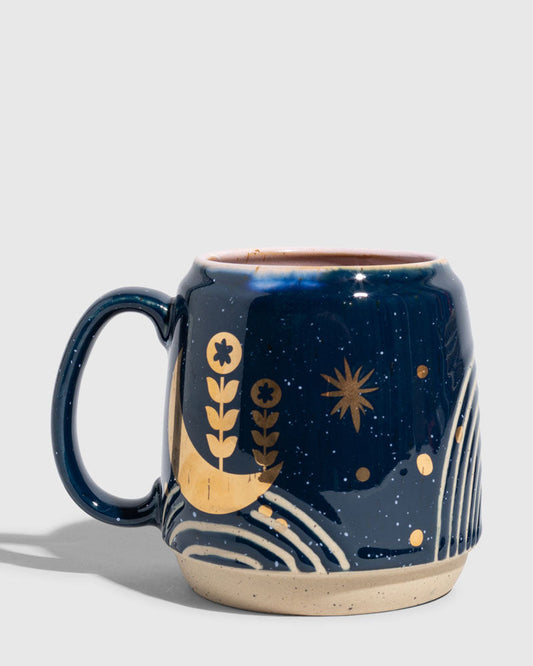 Nightfall Blue 16 oz. Stoneware Mug (Angle): Dark blue stoneware mug with gold moon, botanicals, and star motifs