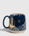 Nightfall Blue 16 oz. Stoneware Mug (Angle): Dark blue stoneware mug with gold moon, botanicals, and star motifs