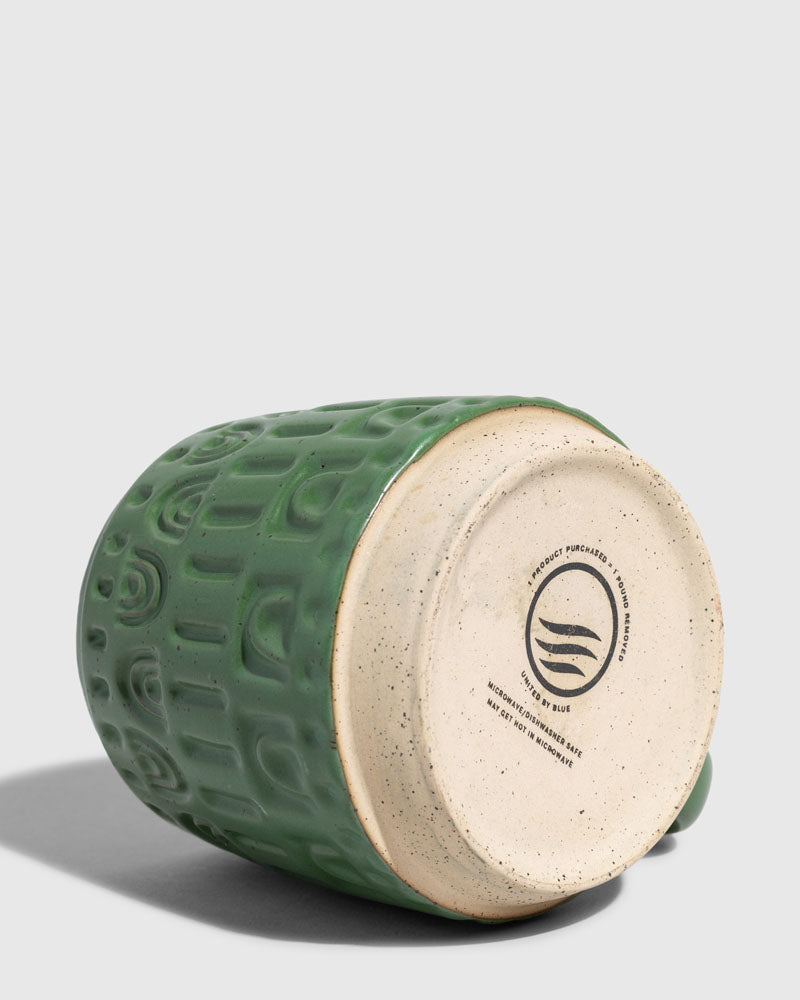 Pine 16 oz. Stoneware Mug (Detail): Bottom of green embossed mug showing unglazed base with brand stamp