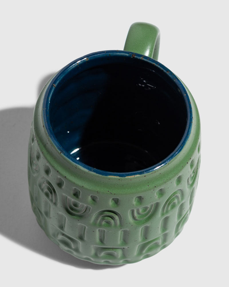 Pine 16 oz. Stoneware Mug (Detail): Top-down view of sage green mug with embossed arch patterns and deep blue interior