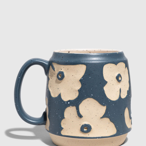 Eclipse Blue 16 oz. Stoneware Mug (Angle): Blue speckled stoneware mug with raised cream floral pattern and loop handle