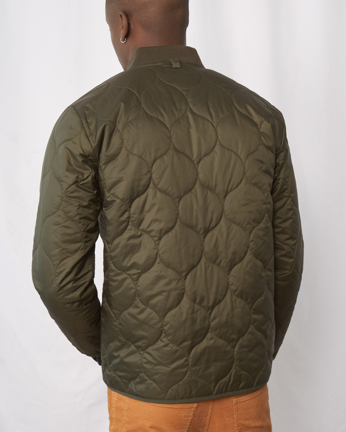 Forest Floor Bison Ultralight Liner Jacket (Back): Olive green quilted bomber jacket with onion-pattern stitching, ribbed collar