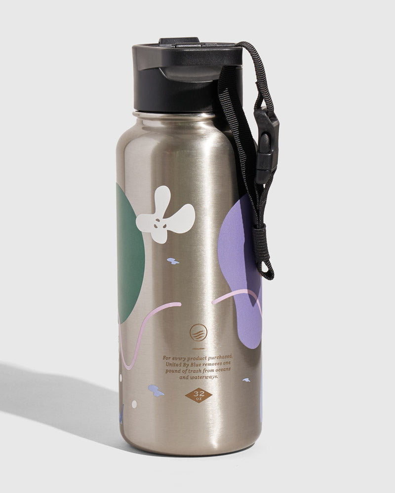 Illuminate Insulated Steel Bottle 32 Oz. (Angle): Silver steel bottle with green, purple, white floral print and black strap