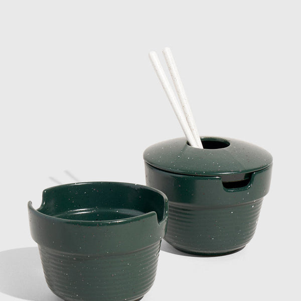 Pine Stoneware Stackable Noodle Bowl Set (Angle): Two dark green speckled ceramic bowls, one lidded with white chopsticks inserted