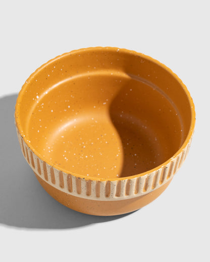 Caramel Stoneware Stackable Bowl (Angle): Round mustard-glazed bowl with divided interior and ribbed textured band