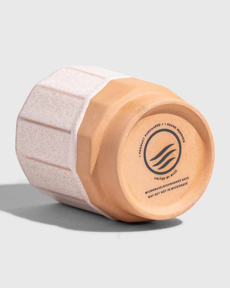 Foxglove 8 oz. Stackable Stoneware Tumbler (Detail): Bottom of white faceted stoneware cup showing unglazed terracotta base with brand logo