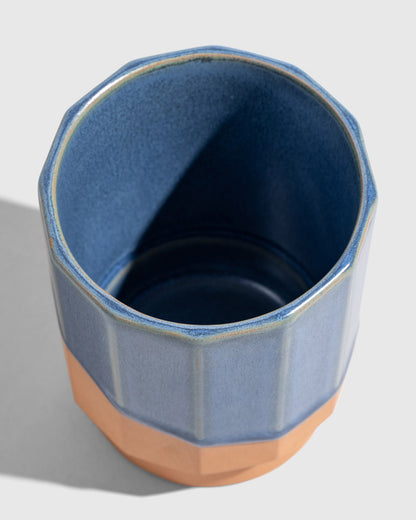 Cobalt 8 oz. Stackable Stoneware Tumbler (Detail): Angled top view inside blue-glazed faceted tumbler with terracotta base