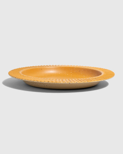 Caramel Stoneware Stackable Plate (Angle): Round golden-yellow ceramic plate with ribbed textured rim and speckled finish