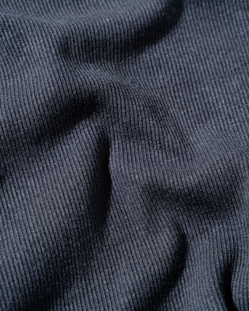 Black EcoKnit™ Ribbed Bike Short (Detail): Close-up of dark charcoal ribbed knit fabric with soft draping folds