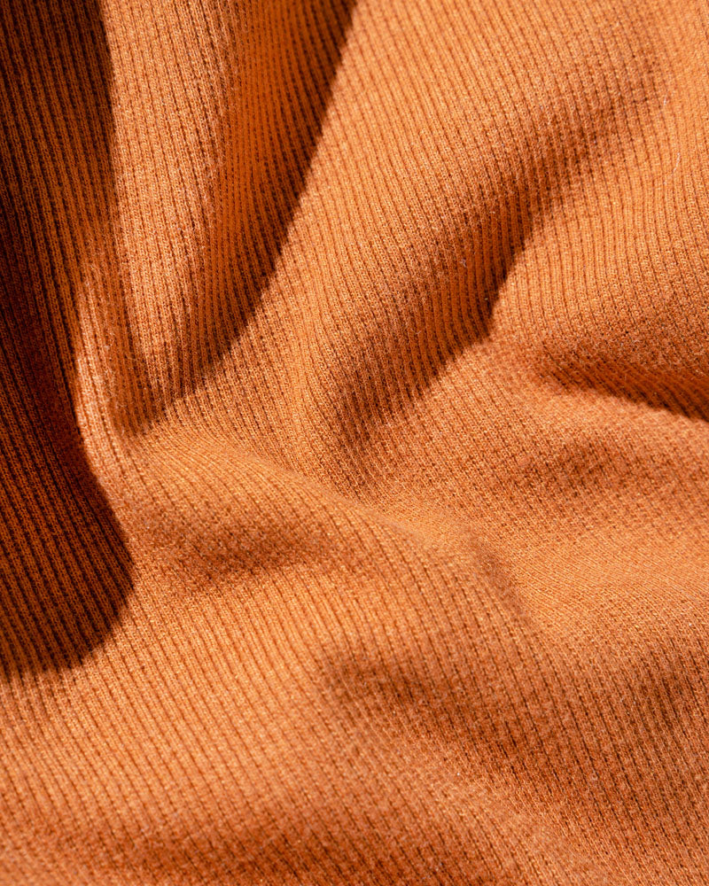 Cinnamon EcoKnit™ Ribbed Bike Short (Detail): Close-up of ribbed rust-orange knit fabric with soft folds and shadows