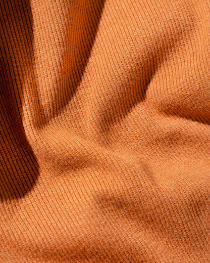 Cinnamon EcoKnit™ Ribbed Bike Short (Detail): Close-up of ribbed rust-orange knit fabric with soft folds and shadows