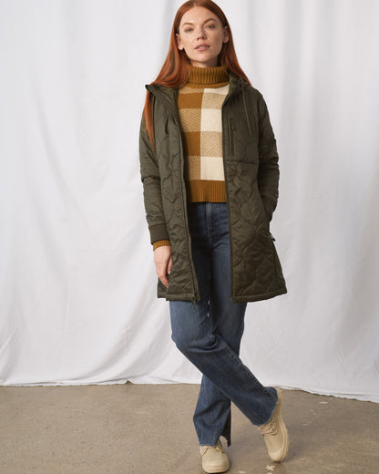 Forest Floor Bison Ultralight Long Liner Jacket (In-use): Woman wearing open olive quilted long coat with hood, walking forward